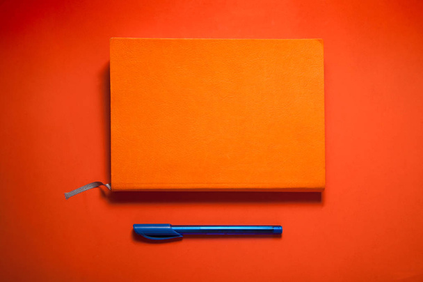 σημειωματάριο με ένα στυλό πάνω σε κόκκινο φόντο - Φωτογραφία, εικόνα