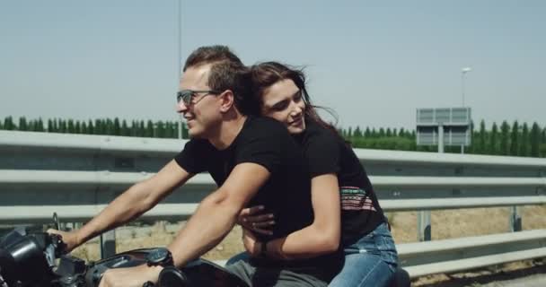 Lovely couple portrait have a ride on a big black motorcycle on the motorway in the summer , little windy and sunny day. 4k - Metraje, vídeo
