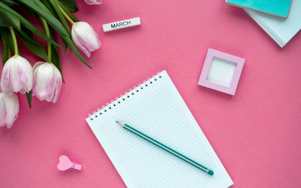 Woman's desktop with notepad, pencil and tulips. - planning women's day. Top view - 写真・画像