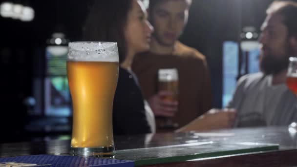 Enfoque selectivo en un vaso de cerveza, gente bebiendo en el pub en el fondo
 - Imágenes, Vídeo