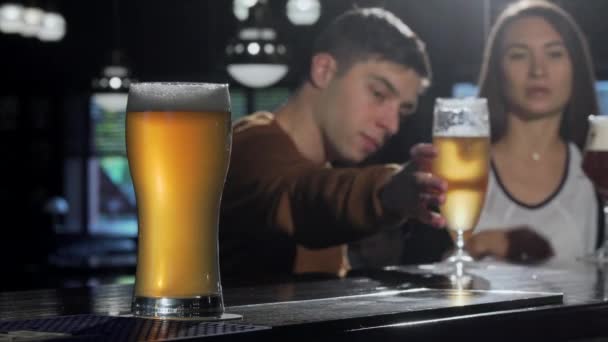 Un vaso de sabrosa cerveza en primer plano, un par de cervezas tintineantes en la parte posterior del pub
 - Metraje, vídeo