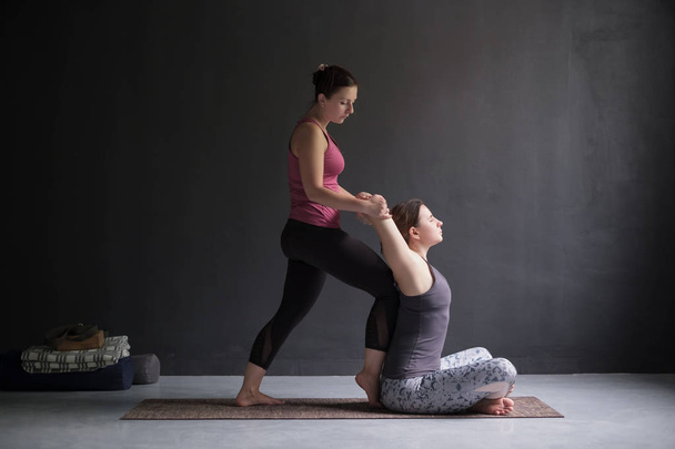 vrouw hielp haar vriend te openen van de schouders en borst doen yoga asana, - Foto, afbeelding