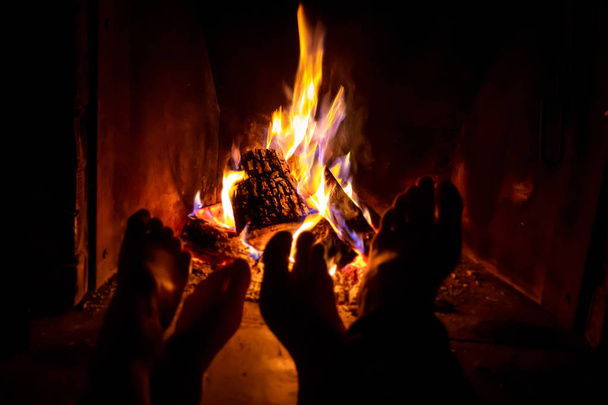 Le gambe nude di giovane donna e uomo sono riscaldate dal fuoco aperto nel camino
 - Foto, immagini