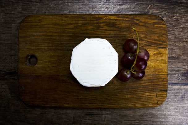 Camembert met druiven aan boord - Foto, afbeelding