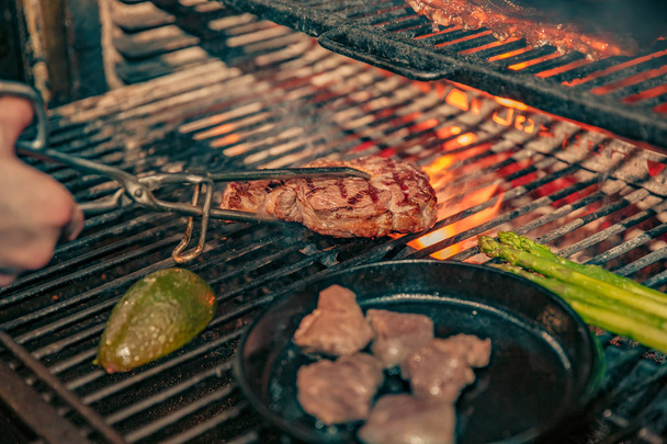 Gros plan de quelqu'un qui fait cuire un steak savoureux sur un feu
 - Photo, image