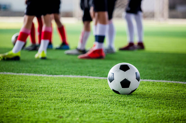 Piłka nożna zielonej trawy syntetycznej z niewyraźne piłkarzy stojąc przed szkolenia i start gry. - Zdjęcie, obraz