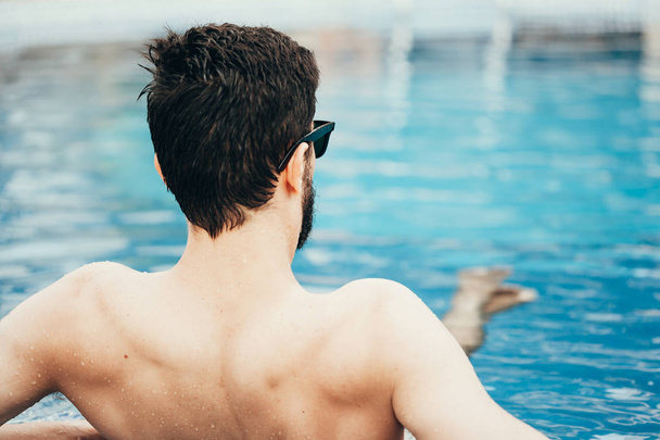 Young man relaxing in pool. Back view - Foto, Imagen