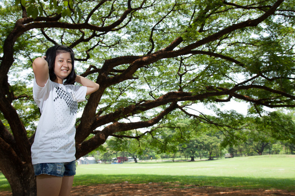Young woman standing under a large tree. - Foto, Imagem