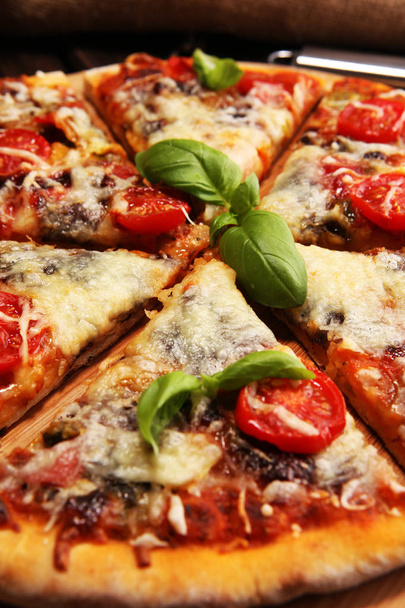 Vegetarian Italian pizza with melted cheese, red tomatoes and green basil on a table decorated by cheese, tomato and red cherry tomatoes - Фото, изображение