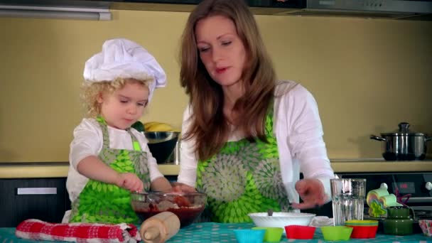 Caucasian woman and cute daughter cooking in kitchen. Family girls having fun - Footage, Video
