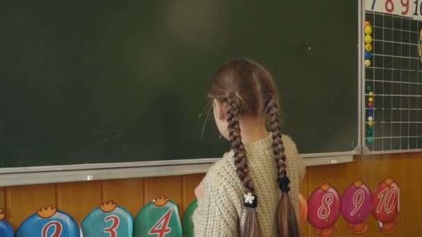 little girl near the board decides the calculations - Video