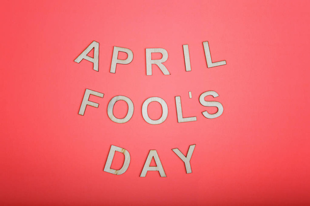 Happy 1 April Fool's day. Beautiful holiday card with wooden letters on pink living coral color background.  - Foto, imagen
