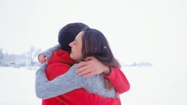 Молодой счастливый мужчина обнимает свою девушку. Эмоциональная влюбленная пара обнимается зимой на снежном фоне
. - Кадры, видео