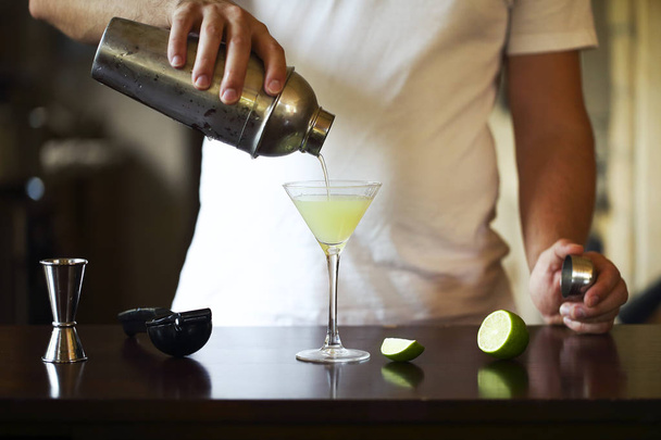 Barman en el trabajo, preparando cócteles. Verter martini en una copa de cóctel. Concepto de servicio y bebidas
 - Foto, imagen