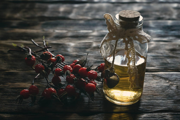 Briar berry essential oil on a wooden board background. - Foto, Bild