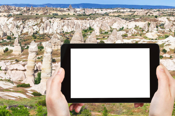 travel concept - tourist photographs of valley with fairy chimney rocks in Goreme National Park in Cappadocia in Turkey on smartphone with empty cutout screen with blank place for advertising - Photo, Image