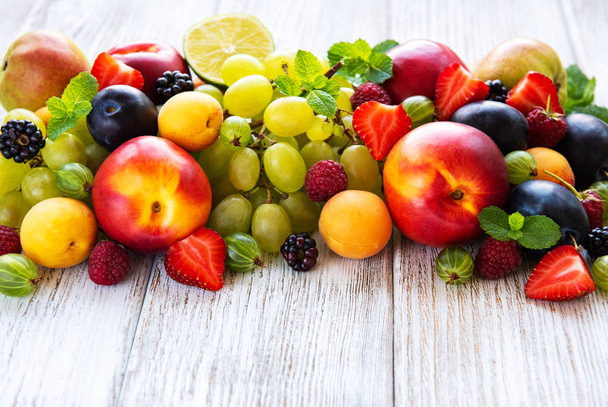 Fresh summer fruits and berries on a white wooden table - Фото, зображення