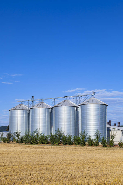 quatre silos d'argent dans le champ après la récolte sous le ciel bleu
 - Photo, image
