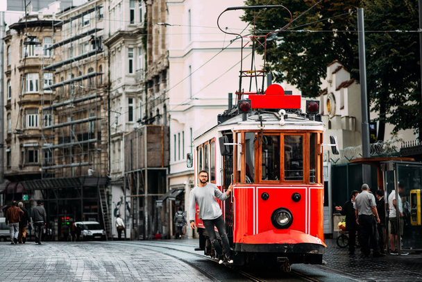 Man in a vintage tram on the Taksim Istiklal street in Istanbul. Man on public transport. Old Turkish tram on Istiklal street, Turkey. Portrait of a smiling young man posing on a city street. - Fotoğraf, Görsel