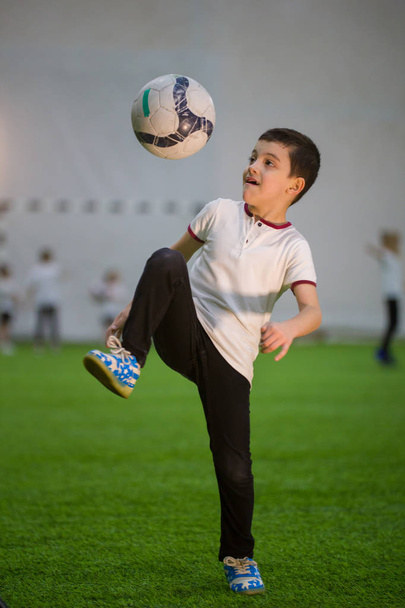 Pieni poika heittää palloa kentällä pelaa jalkapalloa muiden lasten kanssa
 - Valokuva, kuva