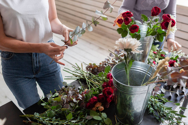 Close-up flowers in hand. Florist workplace. Woman arranging a bouquet with roses, chrysanthemum, carnation and other flowers. A teacher of floristry in master classes or courses - Foto, afbeelding