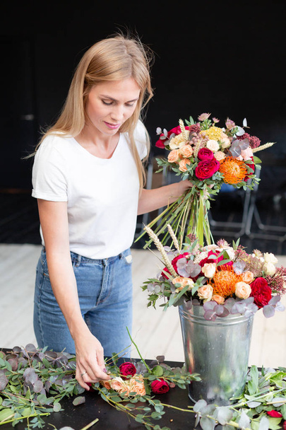 Kukkakauppa työpaikalla. Nainen järjestää kukkakimpun ruusuilla, krysanteemilla, neilikalla ja muilla kukilla. Kukkakaupan opiskelija master-luokissa tai kursseilla
 - Valokuva, kuva