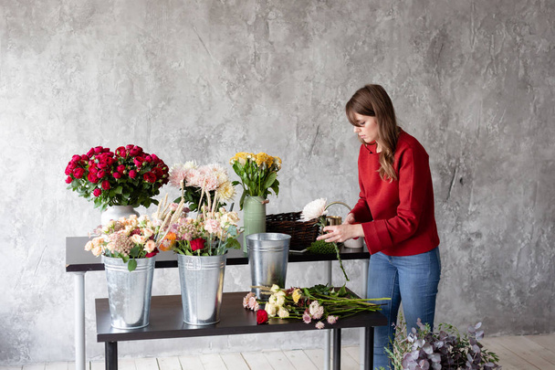 花屋の職場。バラ、キク、カーネーション、他の花で花束をアレンジする女性。マスター クラスやコースのフローリストの先生 - 写真・画像