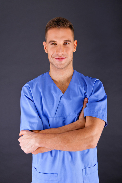 Doctor over dark background in blue shirt - Fotó, kép