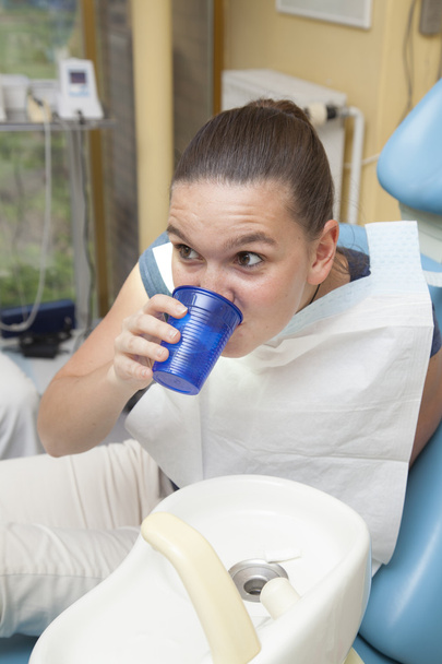leuk meisje mond spoelen na haar tanden gecontroleerd door arts - Foto, afbeelding