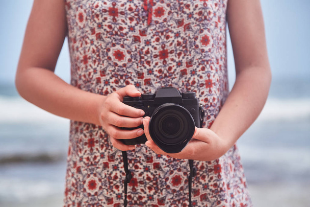 Μια νεαρή κοπέλα κρατώντας μια φωτογραφική μηχανή. - Φωτογραφία, εικόνα