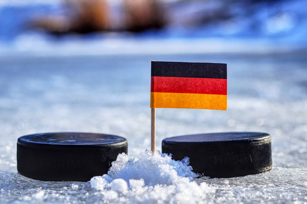 eine Deutschlandfahne auf einem Zahnstocher zwischen zwei Hockeypucks. Deutschland spielt bei der WM in der Gruppe A. WM 2019 in der Slowakei. - Foto, Bild