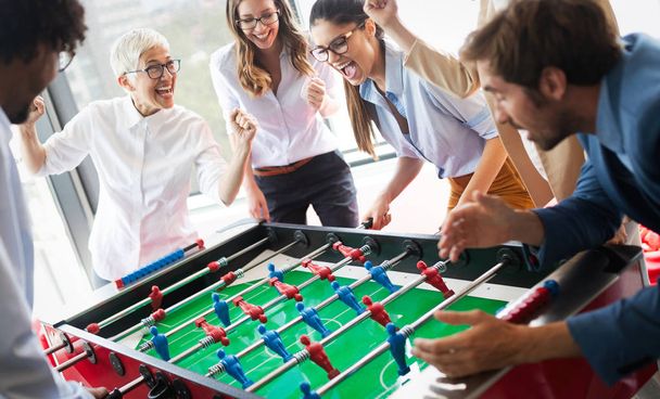 Multicultural business people celebrating win while playing table football together - Foto, immagini