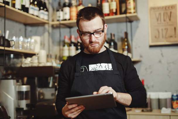 Barista working at the bar with tablet PC for best client service in cafe - Fotó, kép