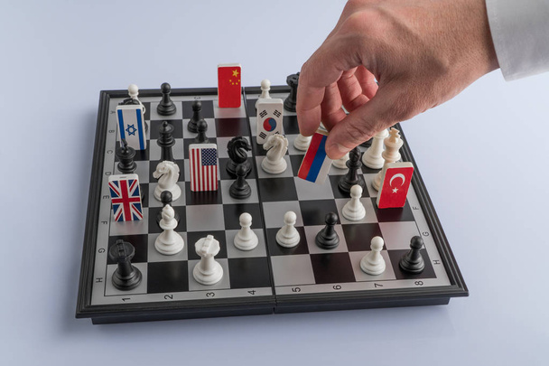 Рука политика перемещает шахматную фигуру с флагом. Концептуальное фото политической игры. ответный ход России
 - Фото, изображение