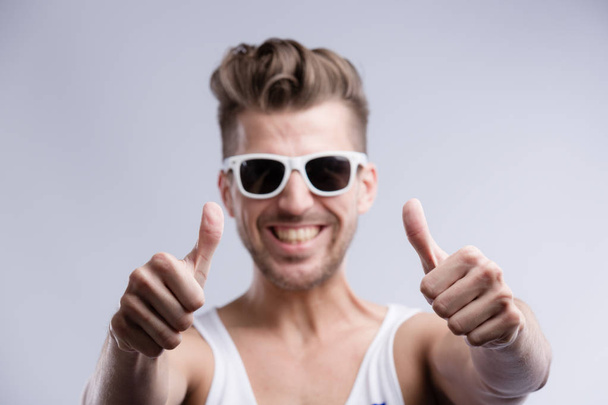 молодий крутий чоловік з сонячними окулярами показує великий палець вгору
 - Фото, зображення