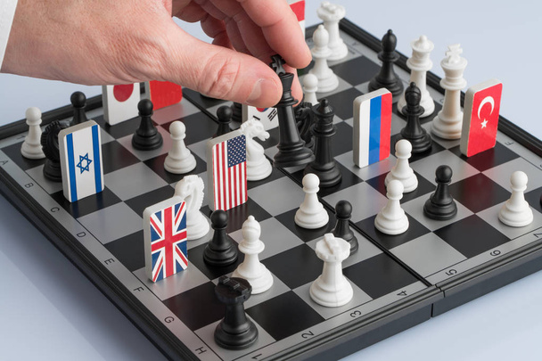 Рука политика перемещает шахматную фигуру. Концептуальная фотография политической игры и стратегии
. - Фото, изображение