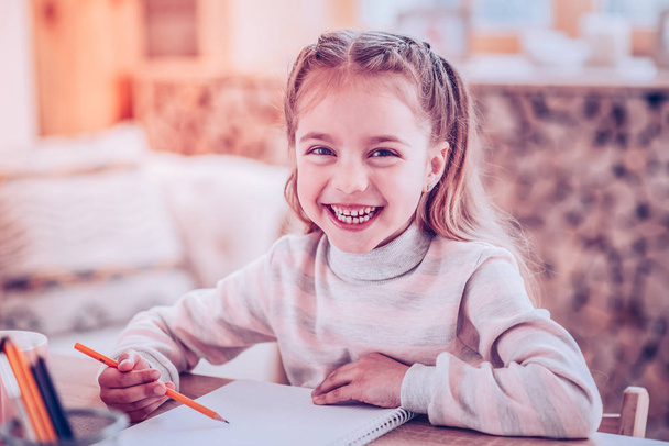 Smiling girl with stylish pigtails joking because of her unclear writing - Fotoğraf, Görsel