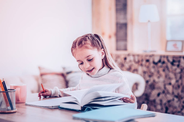 Elegant child finding information in book for homework - Foto, afbeelding
