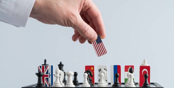 政治家の手は、フラグとチェスの駒を移動します。政治ゲームの概念的な写真。報復の動き米国 - 写真・画像