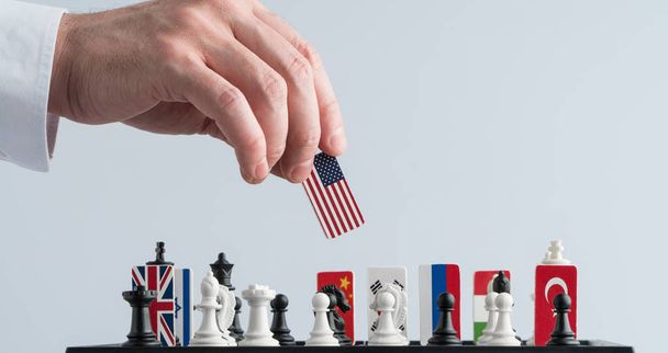 Рука политика перемещает шахматную фигуру с флагом. Концептуальное фото политической игры. ответный ход США
 - Фото, изображение