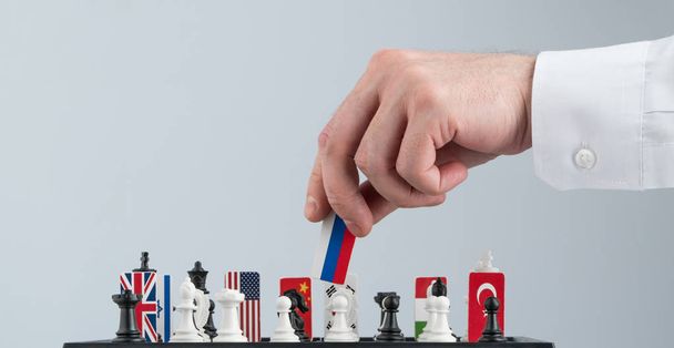 Politicus de hand beweegt een schaakstuk met een vlag. Conceptuele foto van een politiek spel. tegenmaatregelen zet Rusland - Foto, afbeelding