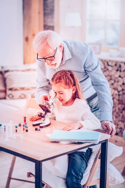 Old man helping kid watching in microscope - Foto, Imagen