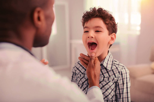 Doctor inspecting the childs mouth and throat - Foto, imagen