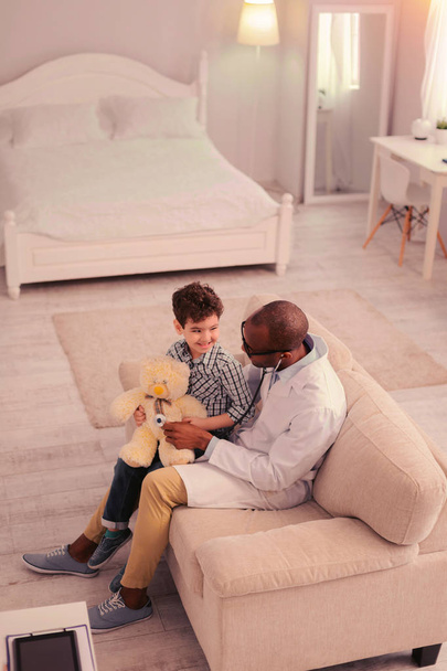 Doctor and a small boy examining a toy - 写真・画像