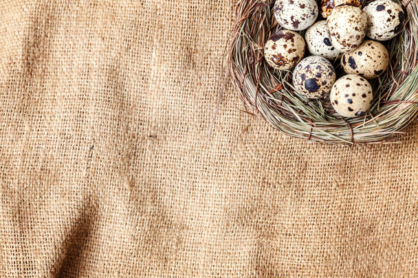 Decoración de Pascua con huevo en nido sobre fondo de lino rústico marrón. Concepto de Pascua. Piso poner espacio de copia vista superior. Tarjeta de felicitación de primavera
 - Foto, imagen