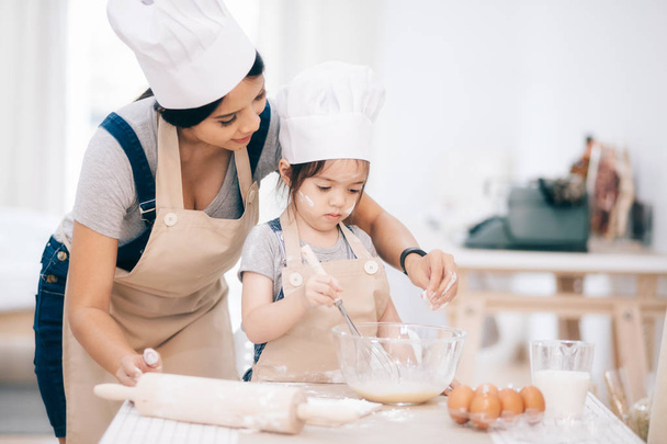Mère et fille utilisant un rouleau à pâtisserie ensemble dans la cuisine - Photo, image
