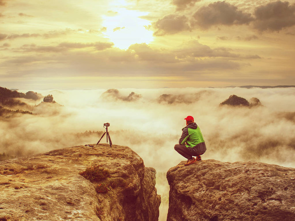 Gelukkig fotoliefhebber geniet van fotografie van Val daybreak in de natuur op klif op rots. Kunstenaar in puur natuur indrukwekkend landschap fotograferen - Foto, afbeelding