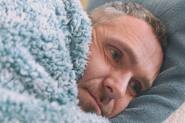 Homem maduro que sofre de depressão está tristemente coberto com um cobertor em sua cama
  - Foto, Imagem