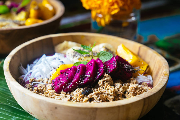 Close up four smoothie bowls made with mango, banana, granola, grated coconut, dragon fruit, chia seeds and mint on colored background - 写真・画像