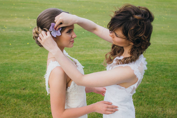 Duas noivas bonitas corrigindo o cabelo no campo verde do clube de golfe
 - Foto, Imagem